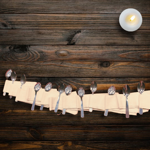 12 cuillères disposées symétriquement entourées chacune d'un linge crème, posées sur une table en bois foncé et une bougie allumée.